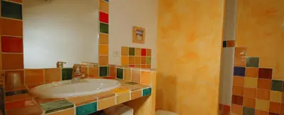 a bathroom with a sink with colorful tiles on the wall at La Tuilière en Luberon in Cadenet