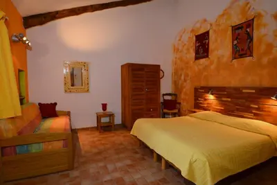 a bedroom with a bed and a chair in a room at La Tuilière en Luberon in Cadenet