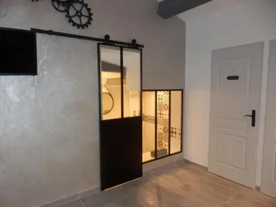 a room with a glass door and a white wall at Gite Le city en Provence in Lambesc
