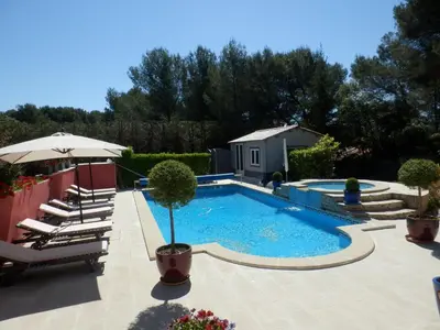 a swimming pool in a yard with chairs and an umbrella at Gite Le city en Provence in Lambesc