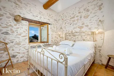 a bedroom with a white bed in a stone wall at Mas La Miellerie - Charme Authentique et Nature in Simiane-la-Rotonde