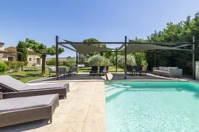 a swimming pool with a patio and an umbrella at Mas Oréa Sous la glycine in Gordes