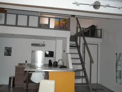 a room with a kitchen and a loft bed at Miel de Lavande in LʼIsle-sur-la-Sorgue