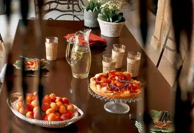 a table with a pizza and a bowl of fruit at Villa Grenache, La Bastide de Marie, Villa avec services in Ménerbes