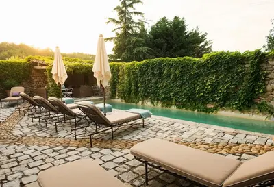 a patio with chairs and umbrellas next to a pool at Villa Grenache, La Bastide de Marie, Villa avec services in Ménerbes