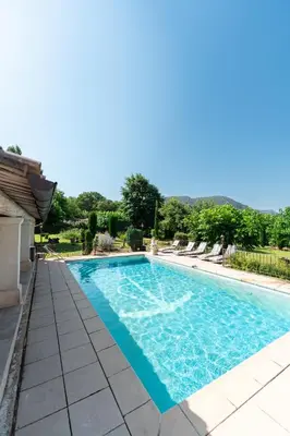 a swimming pool with chairs around it at Bastide Les Basses Royères in Robion en Luberon