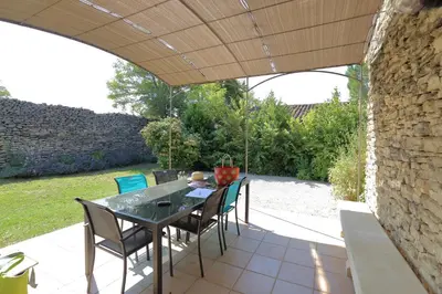 a patio with a table and chairs and a stone wall at Au bastidon de Gordes in Gordes