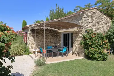 a stone house with a table and chairs in a yard at Au bastidon de Gordes in Gordes