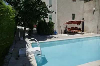a swimming pool with a chair and an umbrella at Les Hauts De Reillanne in Reillanne