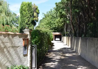 a road with a fence and trees and a tunnel at La Maison Des Invites in Pernes-les-Fontaines