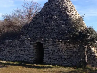 an old stone building with a doorway in a field at La roseraie Bonnieux in Bonnieux