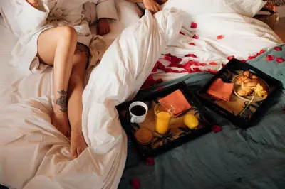 a woman laying in bed with a tray of food and drinks at Maison Florence Ivakno in Coudoux