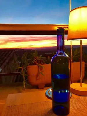 a blue bottle sitting on a table with a lamp at Logis Hôtel Panoramique César in Bonnieux