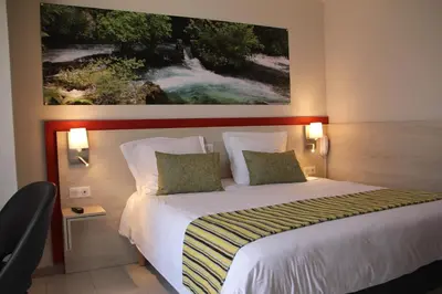 a bedroom with a bed with a painting on the wall at Hôtel Saint Louis in Le Thor