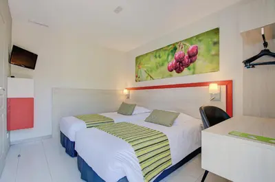 a hotel room with two beds and a painting on the wall at Hôtel Saint Louis in Le Thor