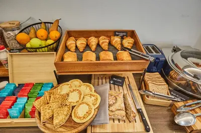 a table topped with baskets of bread and baskets of fruit at Appart'hôtel Odalys City - Aix en Provence Centre Rotonde in Aix-en-Provence