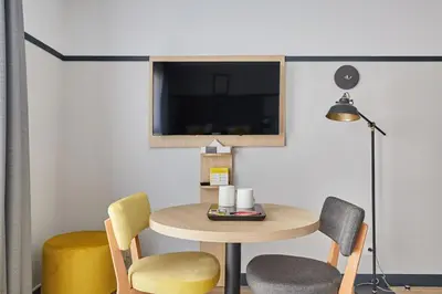 a room with a table and chairs and a tv at Appart'hôtel Odalys City - Aix en Provence Centre Rotonde in Aix-en-Provence