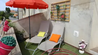 a group of chairs and an umbrella on a balcony at Le Mas Romantique avec Jacuzzi et Sauna privé in Sénas