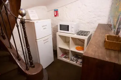 a small kitchen with a microwave on top of a refrigerator at Le palais, hôtel - restaurant in Apt