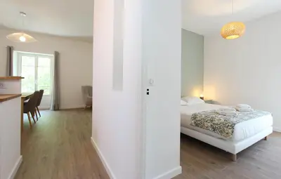 a white bedroom with a bed and a dining room at 