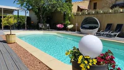 a swimming pool with flowers in pots next to a building at Le Jardin d'Ivana in Oppède