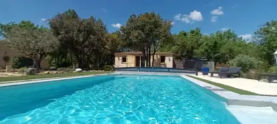 a swimming pool with blue water in a yard at La Pitchounette Mas Val-Chênaie Gordes in Gordes