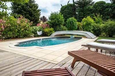 a swimming pool in a garden with a wooden deck at Villa in Provence with private pool in LʼIsle-sur-la-Sorgue