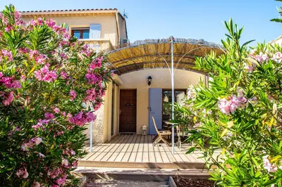 a house with a wooden porch with pink flowers at Villa in Provence with private pool in LʼIsle-sur-la-Sorgue