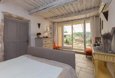 a bedroom with a bed and a large window at La Louvière des Bruyères in Robion en Luberon