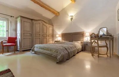 a bedroom with a bed and a table and a desk at La Louvière des Bruyères in Robion en Luberon