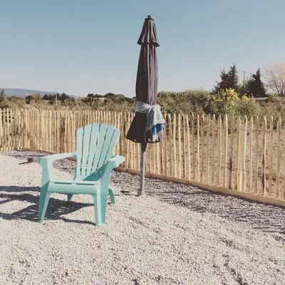 a chair and an umbrella next to a fence at Les intérieurs d'Angèle in Pernes-les-Fontaines