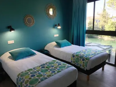 two beds in a room with a window at Hotel Cantosorgue in LʼIsle-sur-la-Sorgue