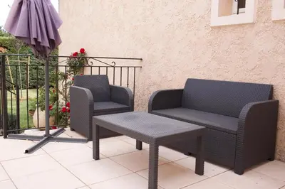 two chairs and a table and an umbrella on a patio at Les murmures du Temps Villa 3 Chambres avec Piscine in Carpentras