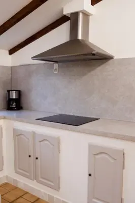 a kitchen with white cabinets and a stove top oven at Les murmures du Temps Villa 3 Chambres avec Piscine in Carpentras