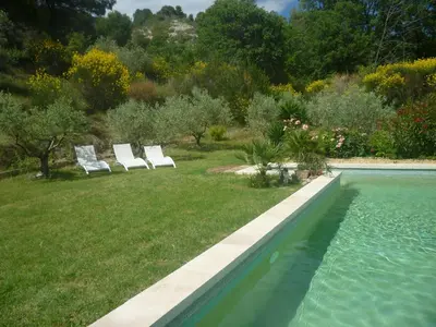 two white lounge chairs sitting next to a swimming pool at Le Paradis in Vaugines