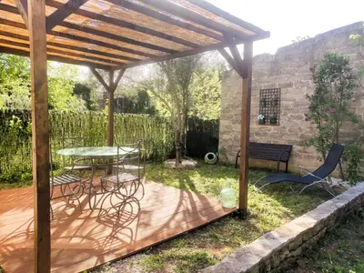 a patio with a table and chairs under a wooden pergola at Maisonnette in Carpentras