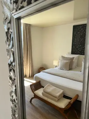 a mirror reflecting a bedroom with a bed and a chair at Le Mas Angelussi - Le Clos du Soleil in Salon-de-Provence