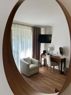 a mirror reflecting a living room with a chair and a desk at Le Mas Angelussi - Le Clos du Soleil in Salon-de-Provence