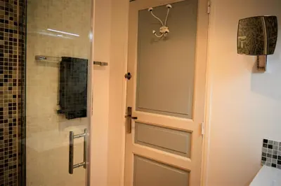 a bathroom with a glass door and a shower at Le Chat Sur Le Toit in Lourmarin