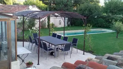 a table and chairs under an umbrella next to a pool at Le Chat Sur Le Toit in Lourmarin