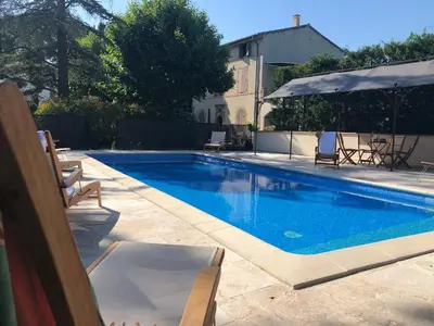 a swimming pool with chairs and an umbrella at Villa Les Cedres in Aix-en-Provence