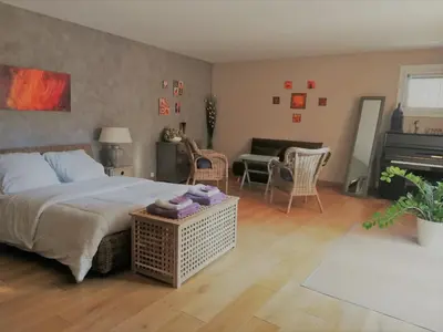 a bedroom with a bed and a living room with a piano at La Goutadou in Cabannes