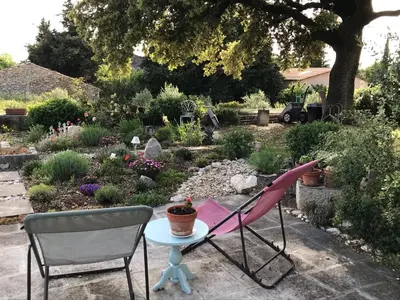 a pink chair and a table in a garden at Oustau du Ventoux in Bédoin