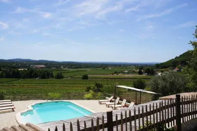 a swimming pool with chairs and a fence at Amandier in Mazan