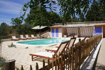 a swimming pool with chairs and a wooden fence at Amandier in Mazan