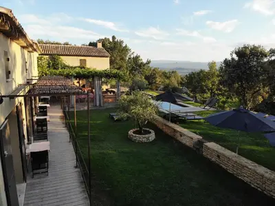 a view of a garden with umbrellas and a patio at Une Sieste en Luberon in Bonnieux