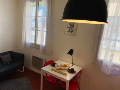 a living room with a table with a lamp and a chair at Granet Studio in Aix-en-Provence