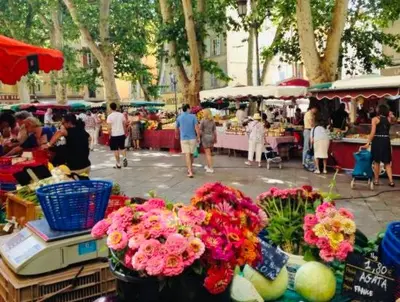 a group of people walking around a market with flowers at Mirabeau Studio in Aix-en-Provence