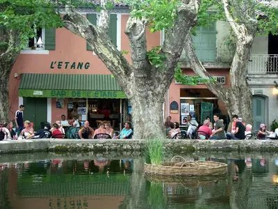 a group of people sitting around a pond in front of a store at La Bastide des Vasses l'Atelier in Cucuron