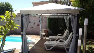 a white umbrella and chairs next to a pool at Brig'Gîte in LʼIsle-sur-la-Sorgue